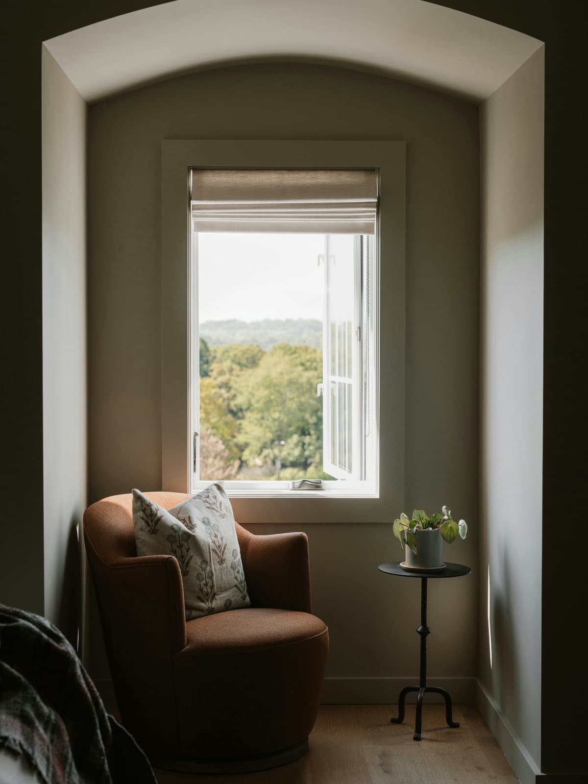 A quiet consultation corner with an arched window, soft natural light, and a reading chair.